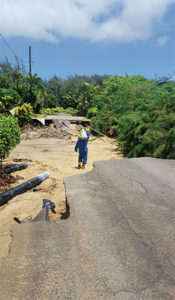 Hawaii Gas’ Darin Yoshioka hauls a 20-pound cylinder across a washed-out road in Kauai. Photo courtesy of Hawaii Gas.