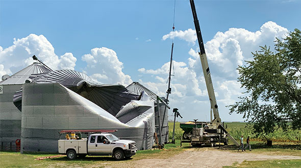 A crane operator prepares to remove grain bins damaged by the derecho near the town of Van Horne in east-central Iowa. Photo by Jay Christie