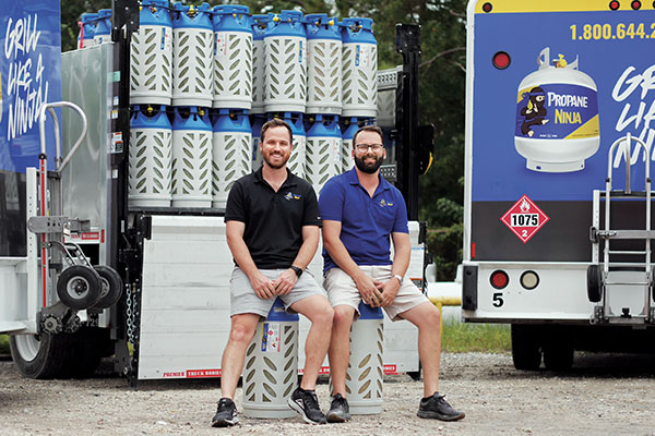 Propane Ninja’s Peter Samuelson, left, and Mike Dodd pose in front of the company’s composite cylinders. The Florida-based company supplies the cylinders for forklifts, hospitality and retail propane exchange. Photo courtesy of Trent Bamberry