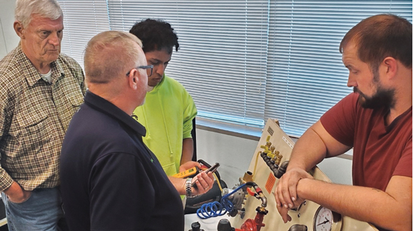 Bergquist’s Trent Johnson, center, and VAPGA’s Dennis Cruise, left, teach ABC’s plumbing students from a propane system board. (Photo by Darryl L. McDonald)