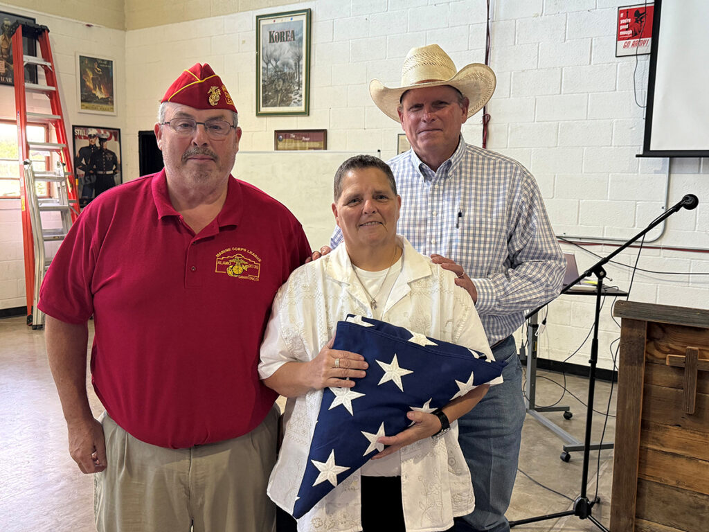 A photo of Bill Hassard, Heart of Texas Propane's Ingram branch manager, and CEO Mark Riley presenting Georgia Wells with an American flag. (Photo courtesy of Heart of Texas Propane)